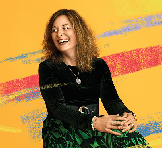 A man in commencement regalia holds up his degree with Gonzaga University written on it